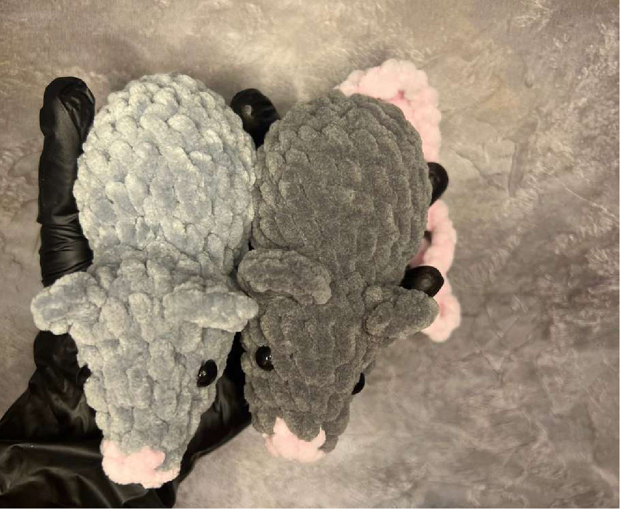 A top-down view of two crocheted mice, highlighting their heads and front paws.
