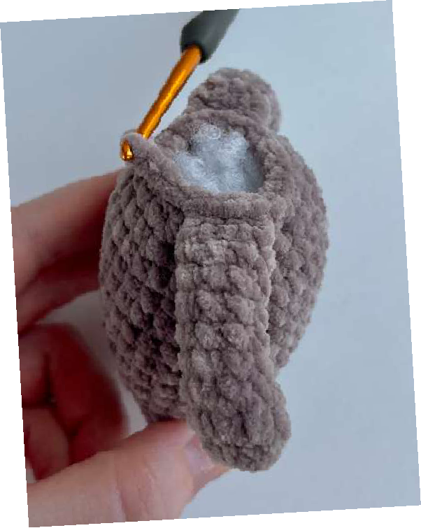 Crocheted bear body with arms being attached