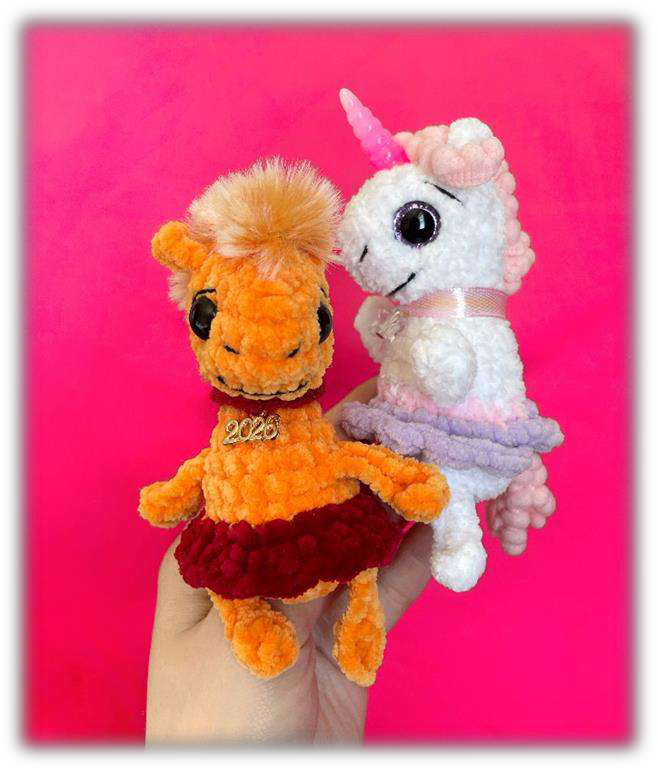 An orange crochet horse and a white crochet unicorn variation.
