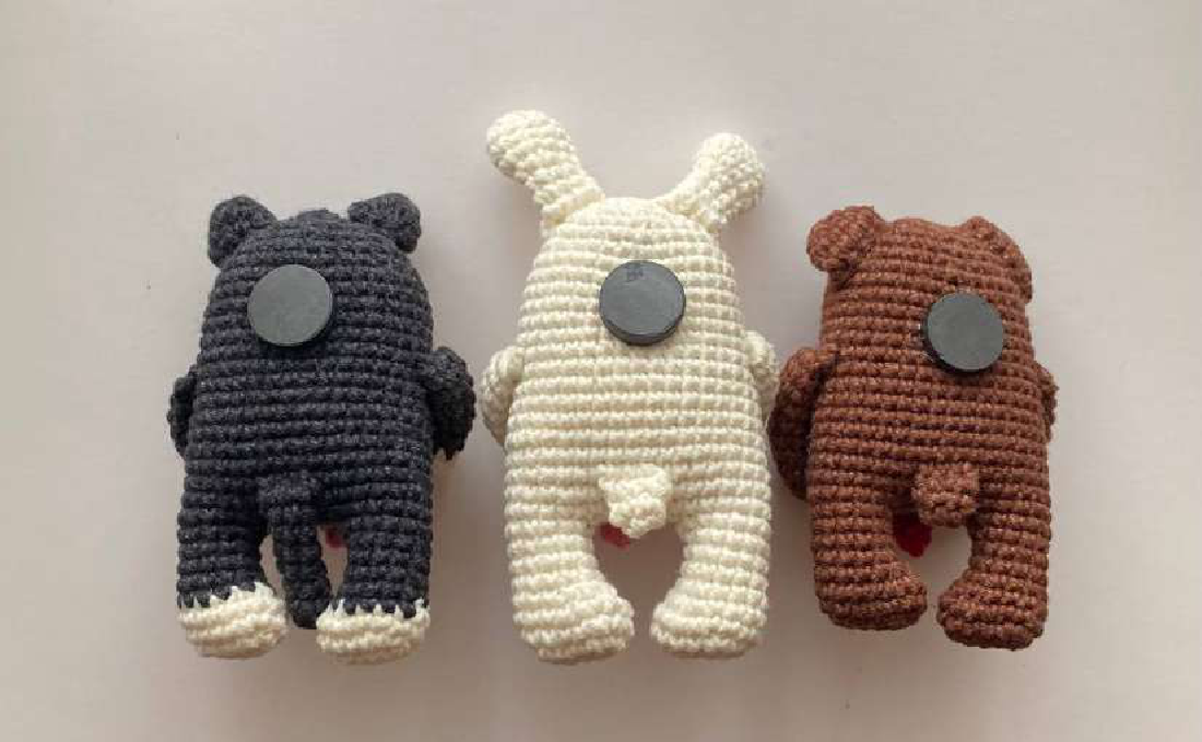 Back of three crocheted figures with magnets attached