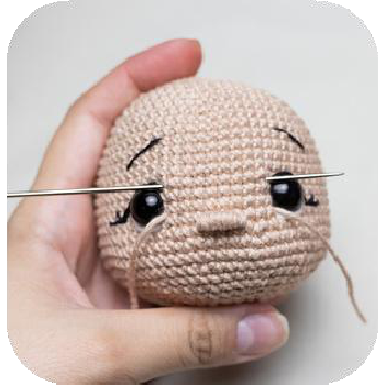 Finished embroidered nose on amigurumi doll