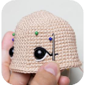 Preparing to cinch doll's eyes