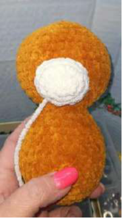 Sewing the legs to the bottom of the bear's body.