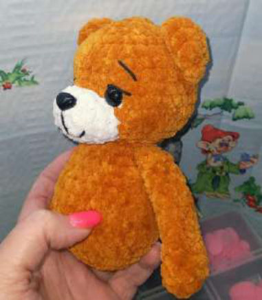 Sewing the arm onto the side of the bear's body.