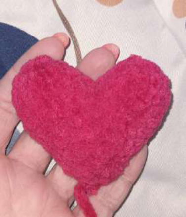Sewing the finished heart onto the bear's paws.
