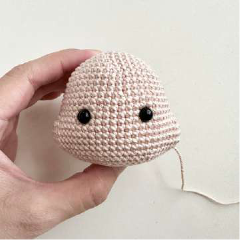 Partially crocheted piglet head with safety eyes inserted