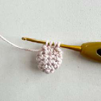 Crocheted orange scarf with a small golden bell attached